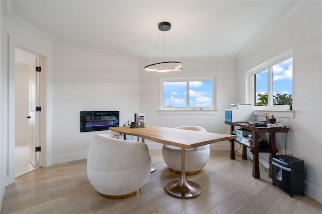 home office featuring a glass covered fireplace, baseboards, ornamental molding, and light wood-style flooring
