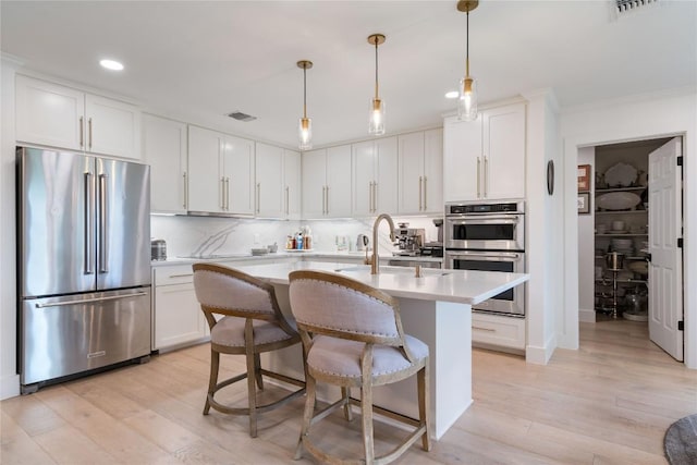 kitchen featuring light countertops, an island with sink, stainless steel appliances, recessed lighting, and visible vents