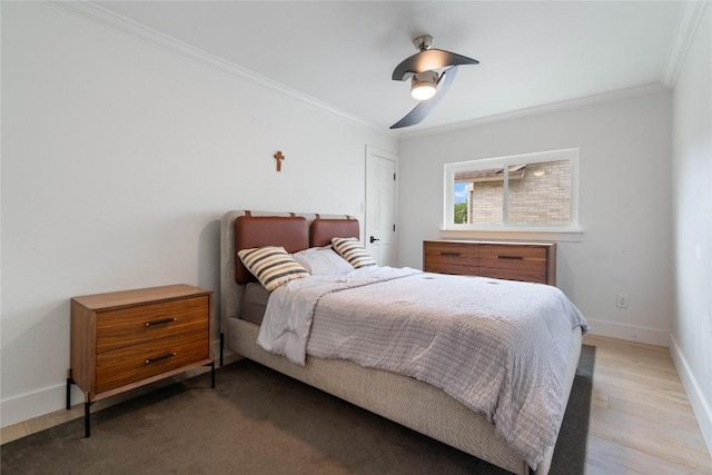 bedroom featuring crown molding, baseboards, a ceiling fan, and wood finished floors