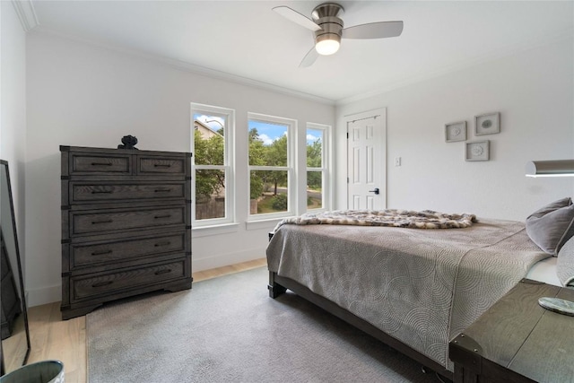 bedroom featuring crown molding, a ceiling fan, and light wood-style flooring
