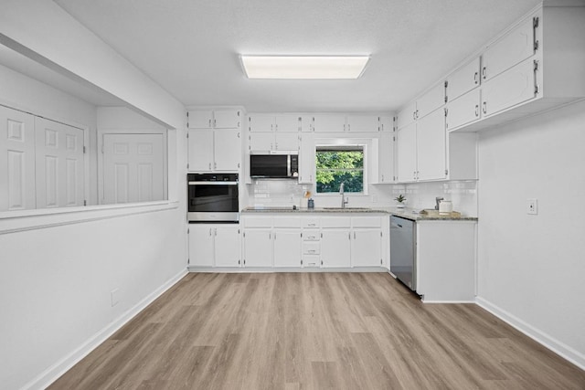 2111 Mardean Ln, Temple, TX 76501 - kitchen featuring stainless steel dishwasher, wall oven, a sink, and light wood-type flooring