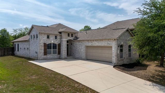 french country inspired facade with a front yard, driveway, stone siding, an attached garage, and fence