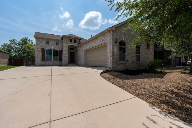 mediterranean / spanish home with concrete driveway, stone siding, an attached garage, and fence