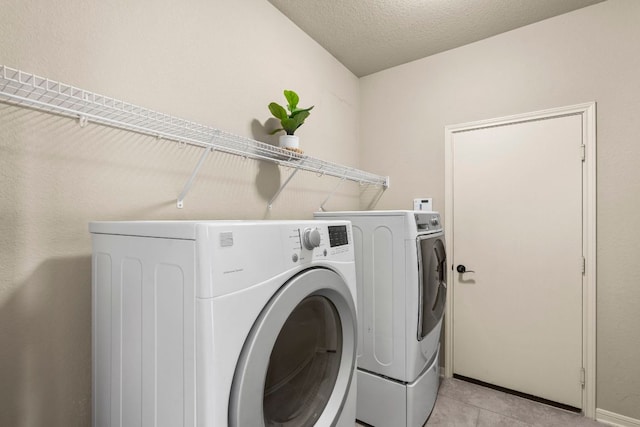 clothes washing area featuring light tile patterned floors, washing machine and clothes dryer, and laundry area