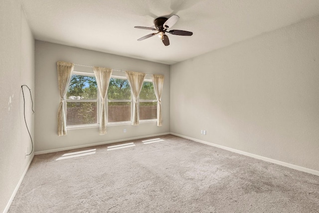 empty room with carpet flooring, ceiling fan, and baseboards