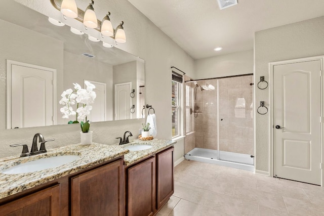bathroom with tile patterned floors, visible vents, a stall shower, and a sink