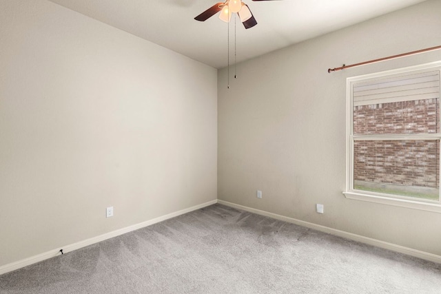 carpeted spare room featuring ceiling fan and baseboards