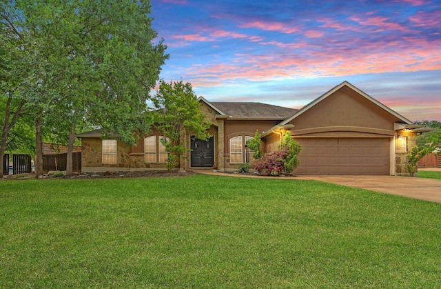 single story home with concrete driveway, stone siding, a lawn, stucco siding, and a garage