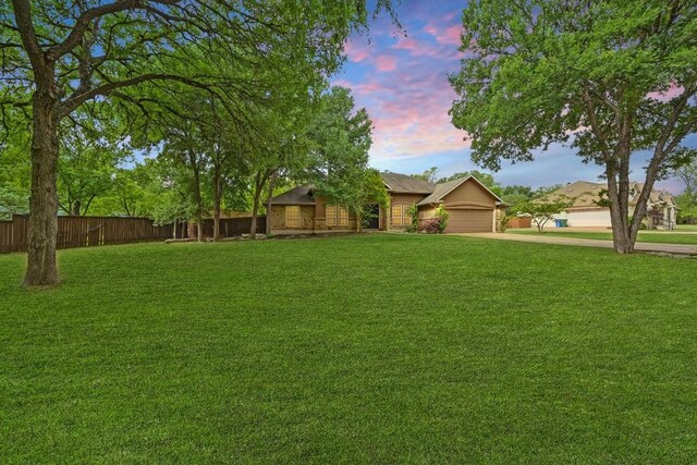 view of yard with fence, driveway, and a garage