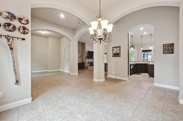 interior space featuring a chandelier, light tile patterned floors, visible vents, baseboards, and arched walkways