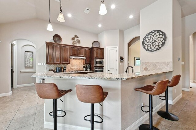 605 River Oaks Dr, Austin, TX 78748 - kitchen with light tile patterned floors, a breakfast bar area, arched walkways, appliances with stainless steel finishes, and tasteful backsplash