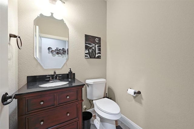 bathroom with toilet, vanity, and baseboards