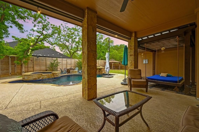 patio terrace at dusk featuring ceiling fan, a fenced backyard, and a pool with connected hot tub