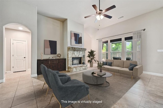 living room featuring visible vents, ceiling fan, baseboards, tile patterned floors, and a stone fireplace