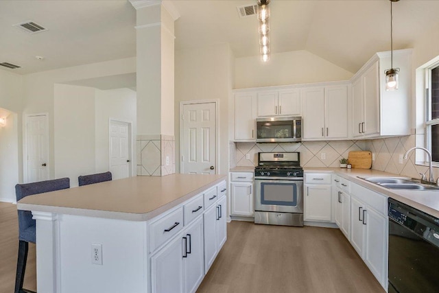 11805 Larch Valley Dr, Austin, TX 78754 - kitchen featuring stainless steel appliances, a breakfast bar, wood finished floors, light countertops, and lofted ceiling