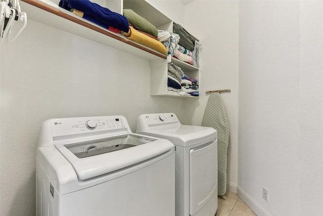 laundry room featuring light tile patterned floors, baseboards, laundry area, and washing machine and dryer