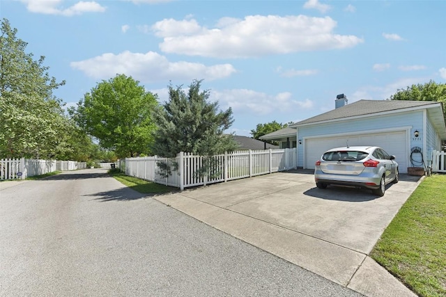 view of side of property with a chimney, fence, and concrete driveway