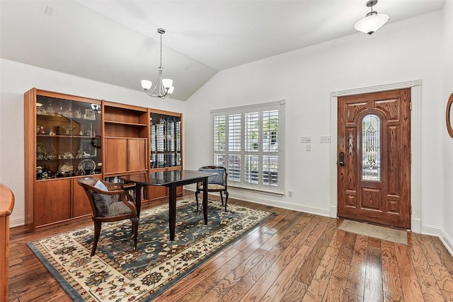 home office with an inviting chandelier, hardwood / wood-style floors, vaulted ceiling, and baseboards