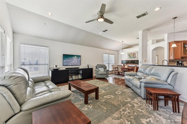 living area with visible vents, arched walkways, a ceiling fan, and lofted ceiling