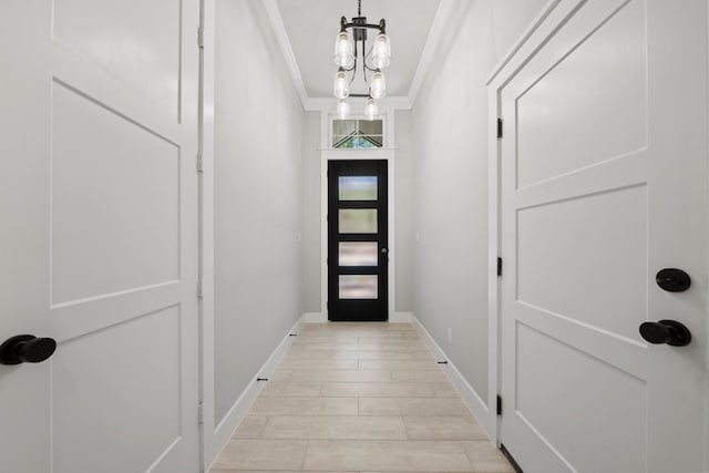 doorway to outside with ornamental molding, light wood finished floors, a notable chandelier, and baseboards