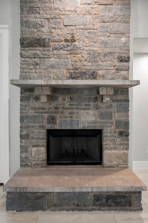 room details with a stone fireplace, wood finished floors, and baseboards
