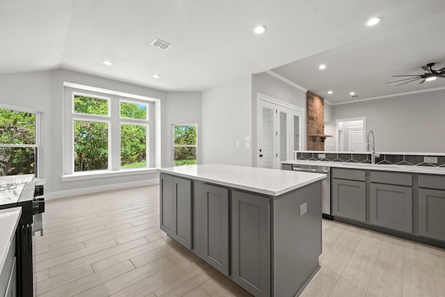 kitchen with gray cabinets, stainless steel dishwasher, a kitchen island, a sink, and visible vents