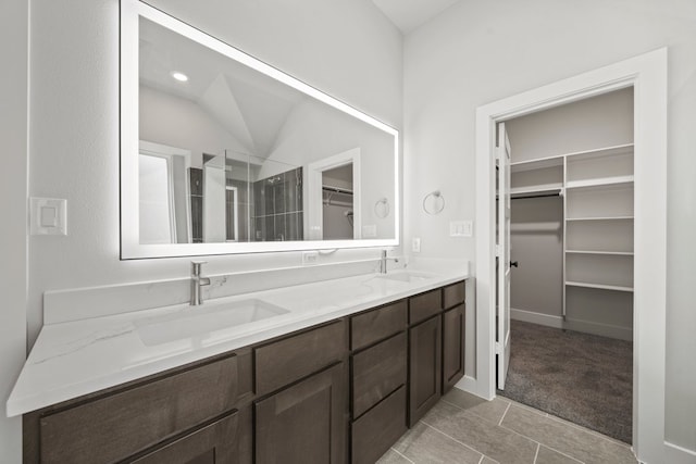 bathroom with double vanity, a spacious closet, tile patterned floors, and a sink