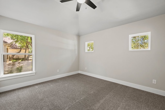 spare room with ceiling fan, vaulted ceiling, dark colored carpet, and baseboards