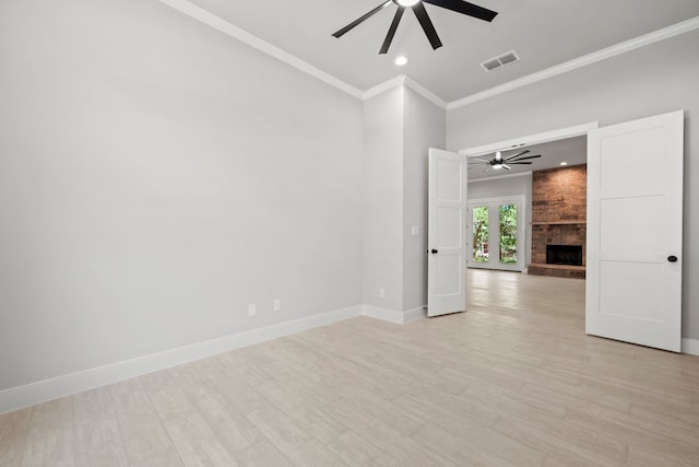 unfurnished room with crown molding, a ceiling fan, a brick fireplace, and visible vents
