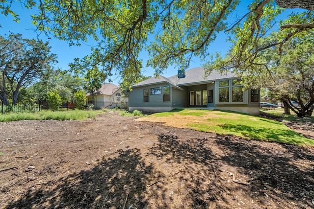 rear view of property with fence and a lawn