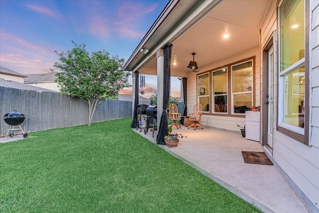 yard at dusk with fence and a patio area