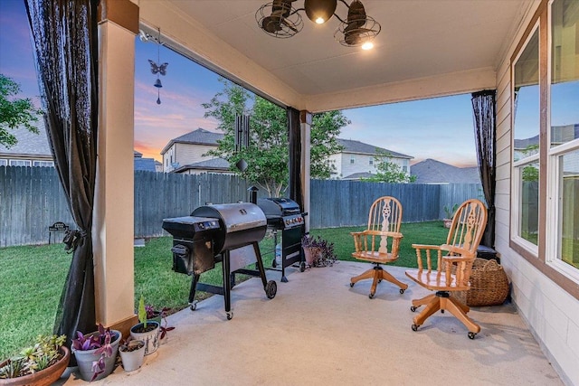 patio terrace at dusk with a ceiling fan, a yard, and a grill