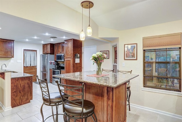 kitchen featuring light stone counters, stainless steel appliances, a kitchen island, a kitchen bar, and light tile patterned flooring
