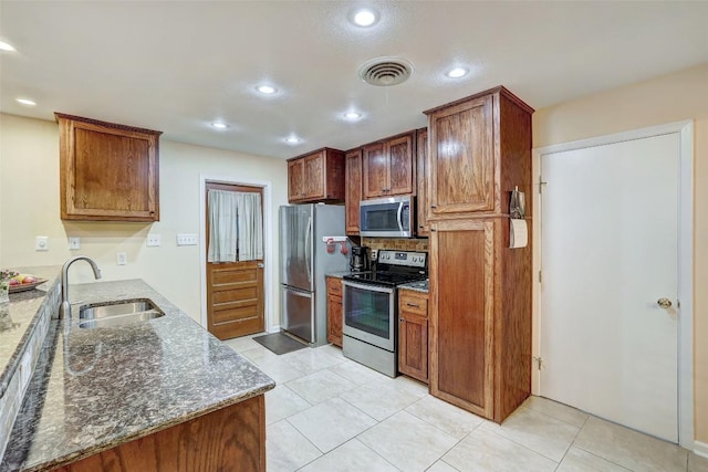 kitchen with dark stone counters, visible vents, appliances with stainless steel finishes, and a sink