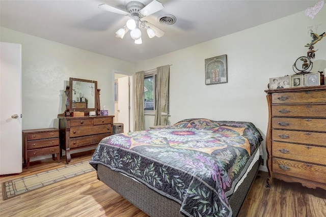 bedroom with wood finished floors, visible vents, and a ceiling fan