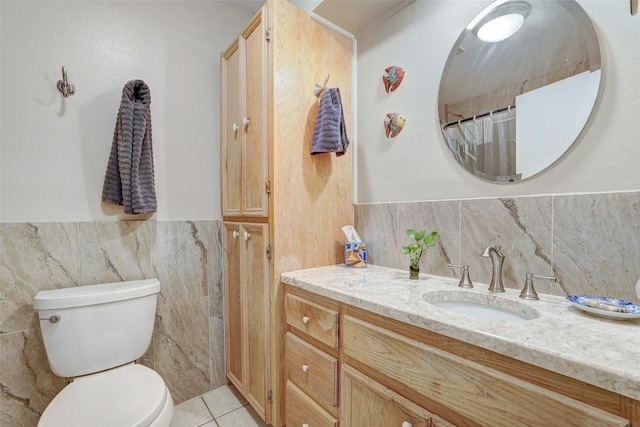 bathroom featuring tile walls, vanity, tile patterned floors, toilet, and wainscoting