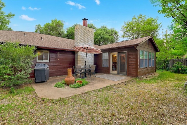 back of house featuring fence, a chimney, a patio area, and a lawn