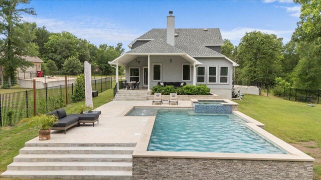 rear view of property featuring a patio, an in ground hot tub, a chimney, stucco siding, and a lawn