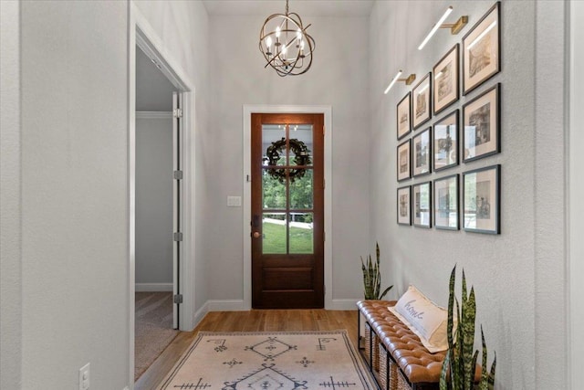 doorway to outside with a chandelier, baseboards, and light wood finished floors