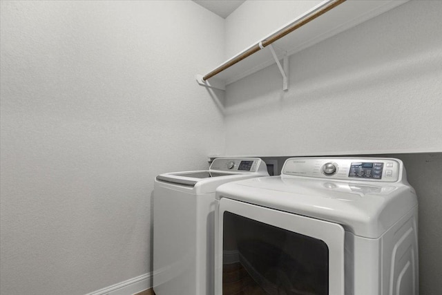 washroom with washing machine and clothes dryer, wood finished floors, and laundry area
