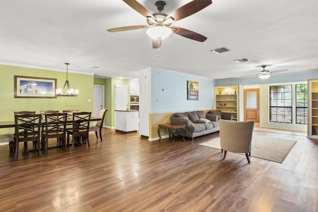 living room with wood finished floors, visible vents, baseboards, and ceiling fan with notable chandelier
