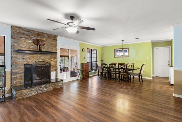 dining area featuring crown molding, a fireplace, wood finished floors, and ceiling fan with notable chandelier