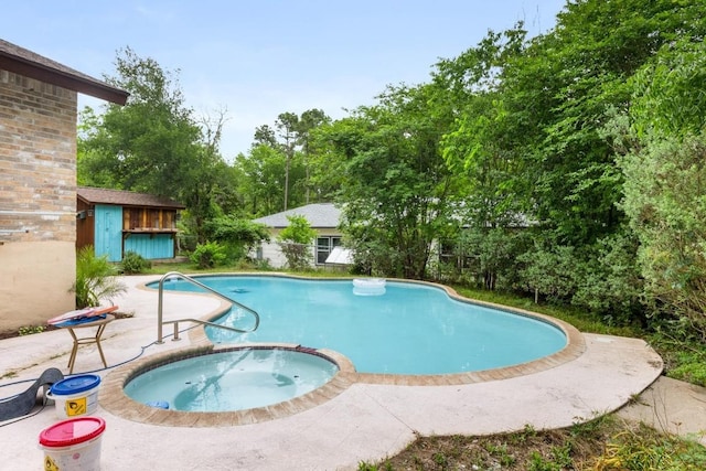 view of pool featuring a pool with connected hot tub, a patio, and an outbuilding
