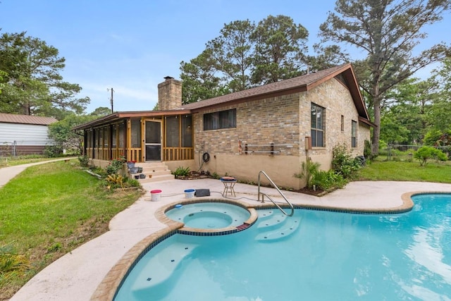 view of pool with fence, a pool with connected hot tub, a patio area, a sunroom, and a lawn