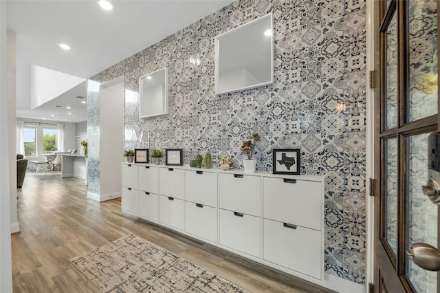 bar with baseboards, wallpapered walls, and light wood finished floors