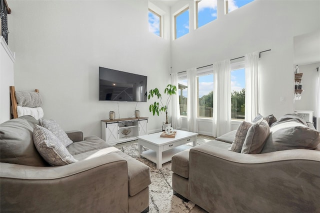 living area with a towering ceiling, wood finished floors, and plenty of natural light