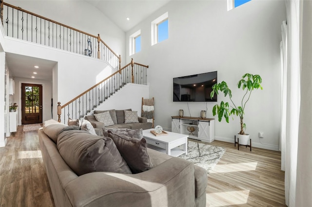living room with recessed lighting, high vaulted ceiling, stairs, baseboards, and wood finished floors