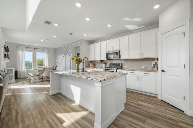 kitchen featuring wood finished floors, stainless steel appliances, backsplash, a sink, and visible vents