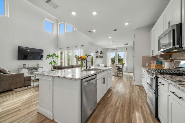 kitchen featuring appliances with stainless steel finishes, open floor plan, visible vents, and a sink