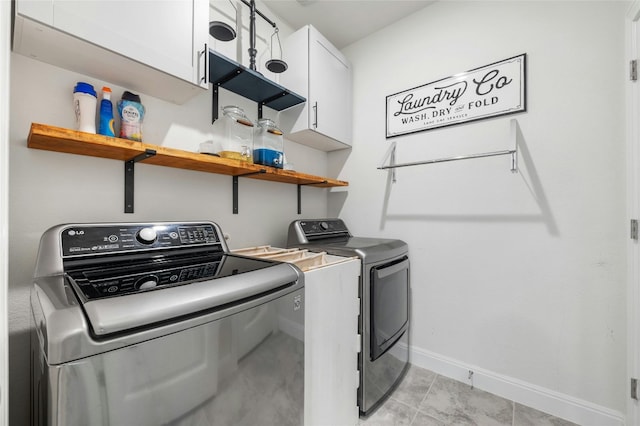 laundry room with light tile patterned floors, independent washer and dryer, cabinet space, and baseboards